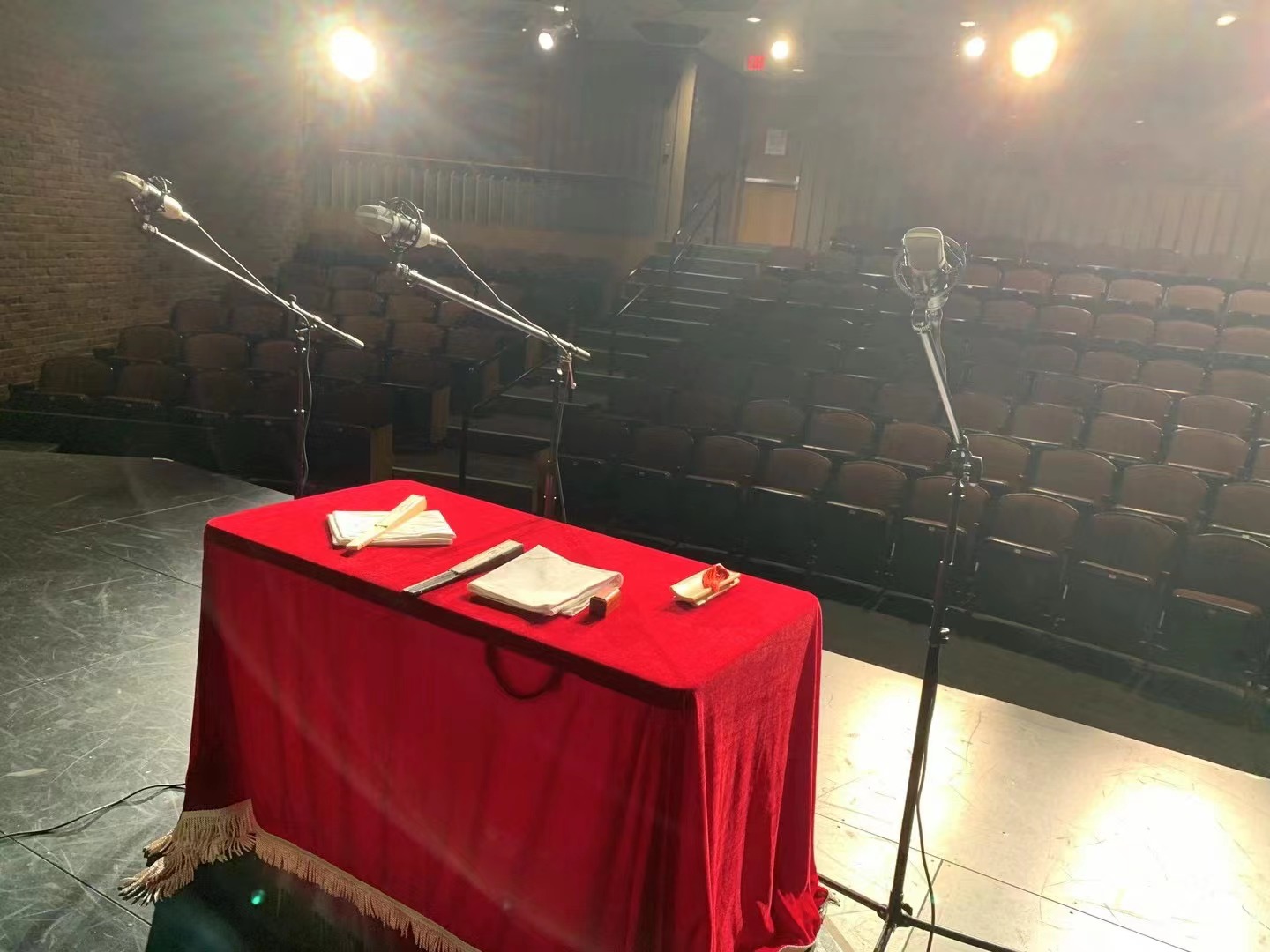 A stage with microphones and a table with a red cloth Description automatically generated